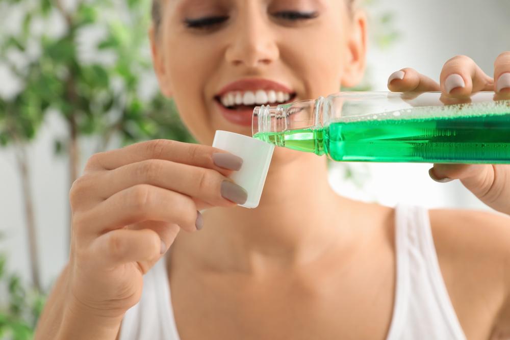 Woman using green mouthwash